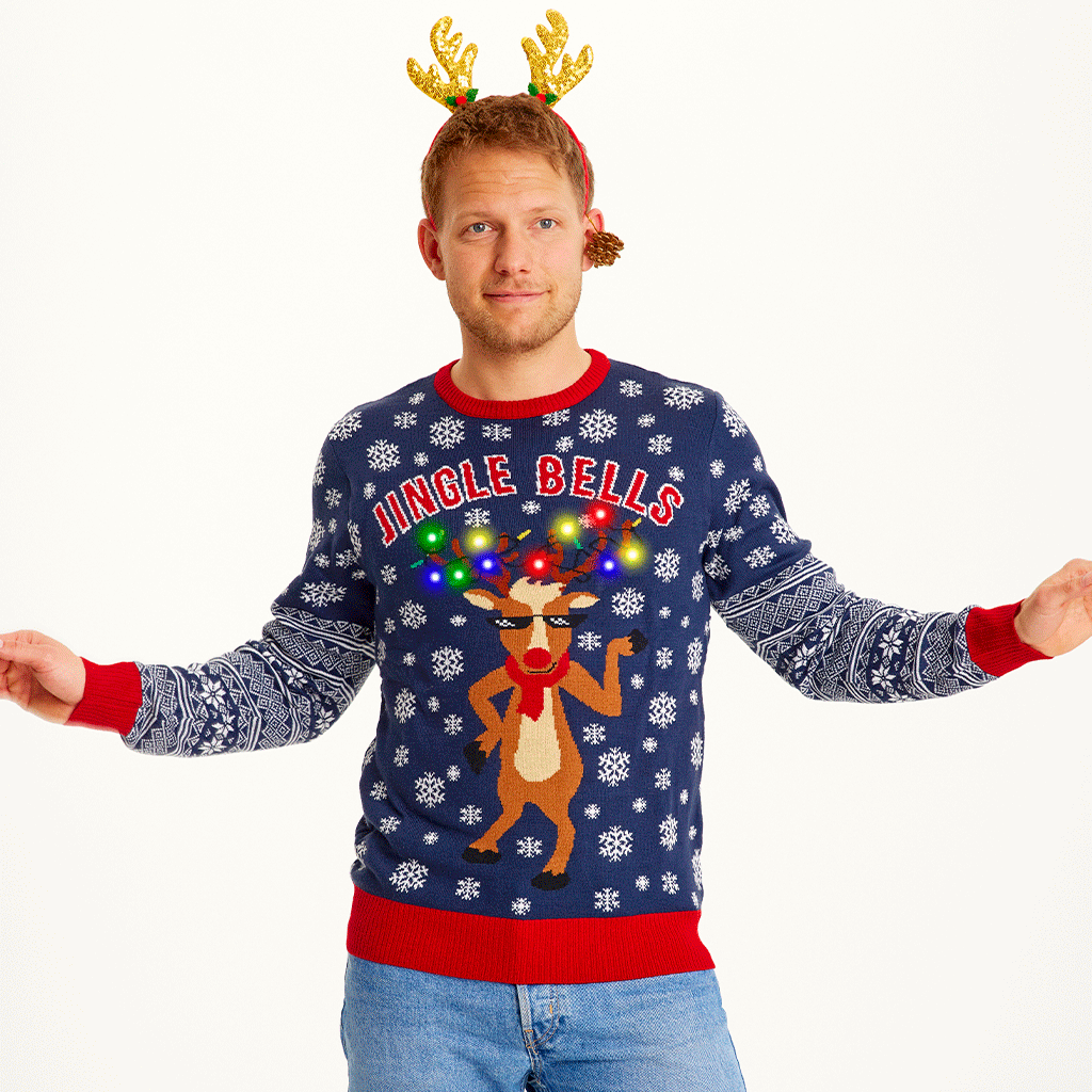 Een poserende man die een blauwe kersttrui draagt met een dansend rendier met lichtjes erop.